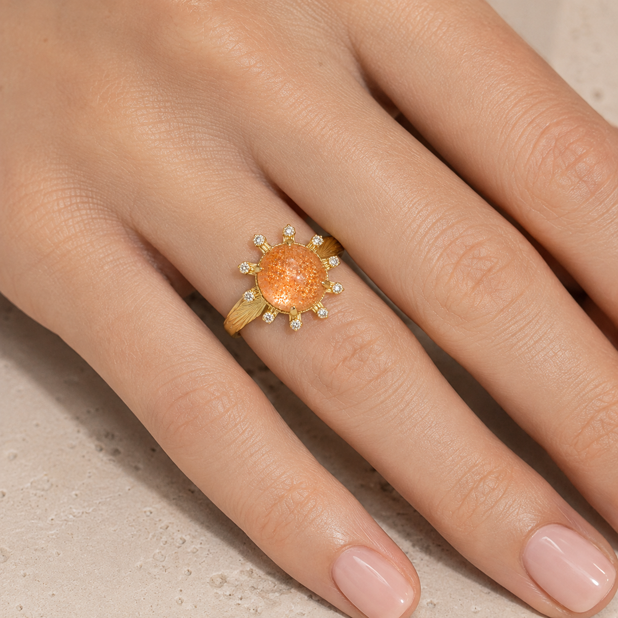 Close-up of a woman wearing the Aurelia round sunstone ring on her ring finger