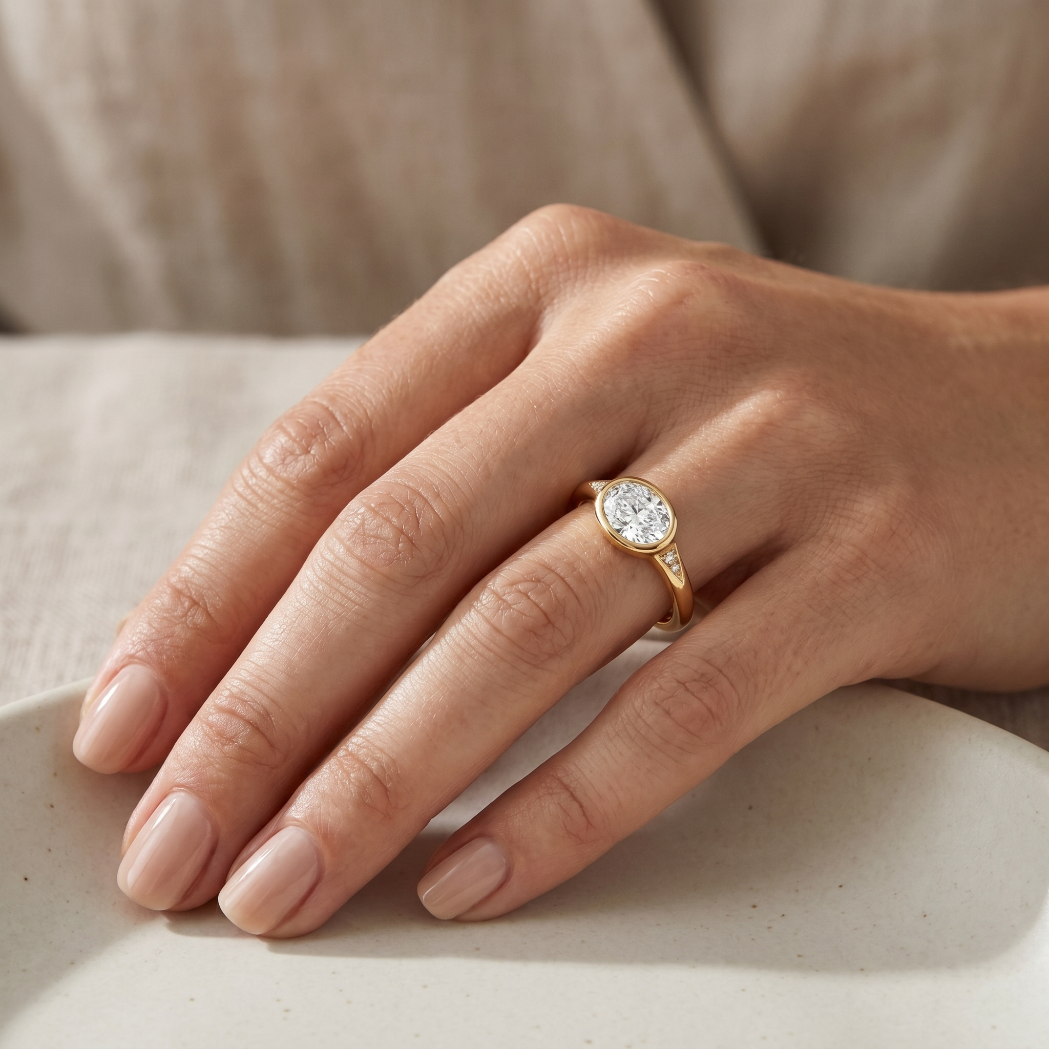 East-west oval lab-grown diamond bezel ring in yellow gold with diamond accent shoulders