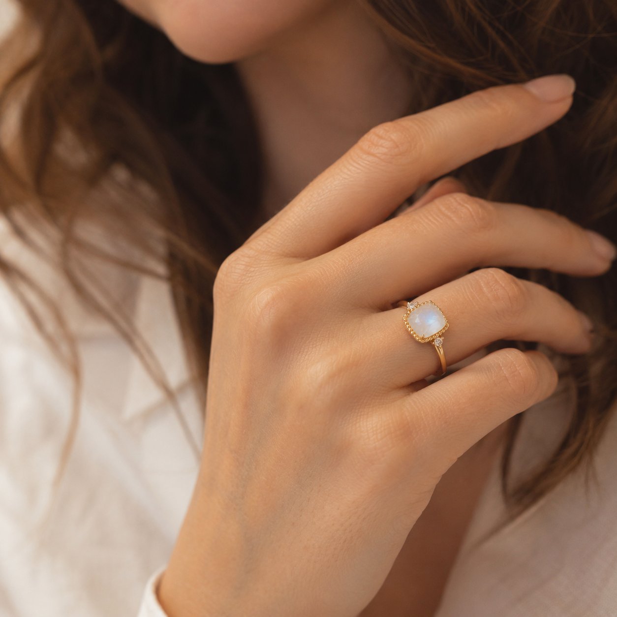 Cushion moonstone gold ring with moissanite accents worn by female model